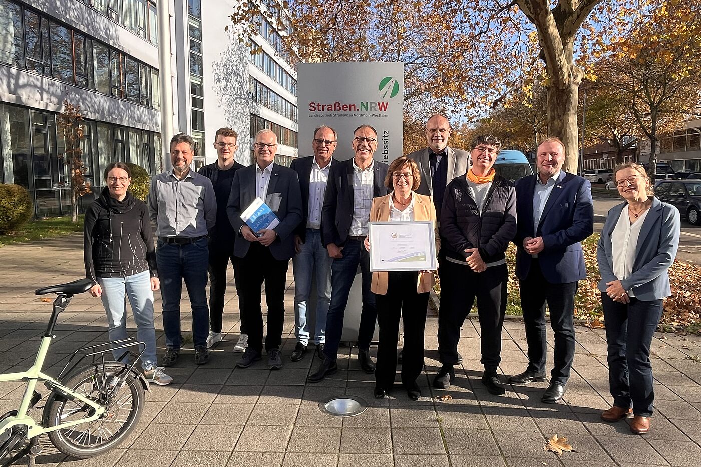 Zertifikatsübergabe (Gold) Straßen.NRW Am 7. November 2025 erhielt der Landesbetrieb Straßenbau Nordrhein-Westfalen (Straßen.NRW) am Betriebssitz Gelsenkirchen das Zertifikat "Fahrradfreundlicher Arbeitgeber" in Gold. Bei der Übergabe anwesend waren (v.l.) Maja Tölke (ADFC Gelsenkirchen), André Friedrich (Leiter Sachgebiet Radverkehr), Timon von Wiecken (Sachgebiet Radverkehr und Radverkehrskoordintor), Marc Zietan (ADFC NRW), Karsten van Dreuten (Leiter Abteilung Verwaltung und Service), Christoph Jansen (Leiter der Region II, designierter Nachfolger von Frau Dr. Beckefeld), Dr. Petra Beckefeld (Direktorin des technischen Bereichs und Sprecherin des Direktoriums), Christian Jung (Leiter Sachgebiet Immobilienstrategie/ bauaufsichtliche Angelegenheiten/TGA/ZD), Andreas K. Bittner (ADFC Projekt "Fahrradfreundlicher Arbeitgeber"), Dr. Sascha Kaiser (Direktor des kaufmännisch-juristischen Bereichs), Daniela Schnickmann (Sachgebiet Radverkehr).