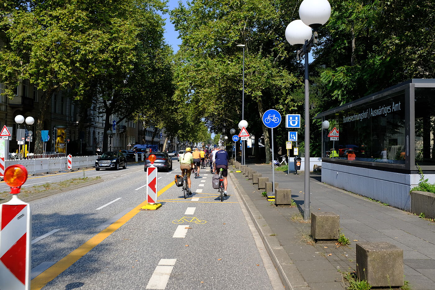 2024-08-Exkursion_Bonn_-_ADFC_NRW__24 Die Adenauerallee, eine wichtige Nord-Süd Achse muss saniert werden. Ein dreimonatiger Verkehrsversuch hat gezeigt, dass der Kfz-Verkehr auf jeweils einer Fahrspur abgewickelt werden kann. Inzwischen hat der Bonner Stadtrat die Schaffung sicherer (teilweise geschützter) und breiter Radinfrastruktur zugestimmt. Damit können die Unibibliothek und ein großes Gymnasium zukünftig auch sicher mit dem Rad erreicht werden.