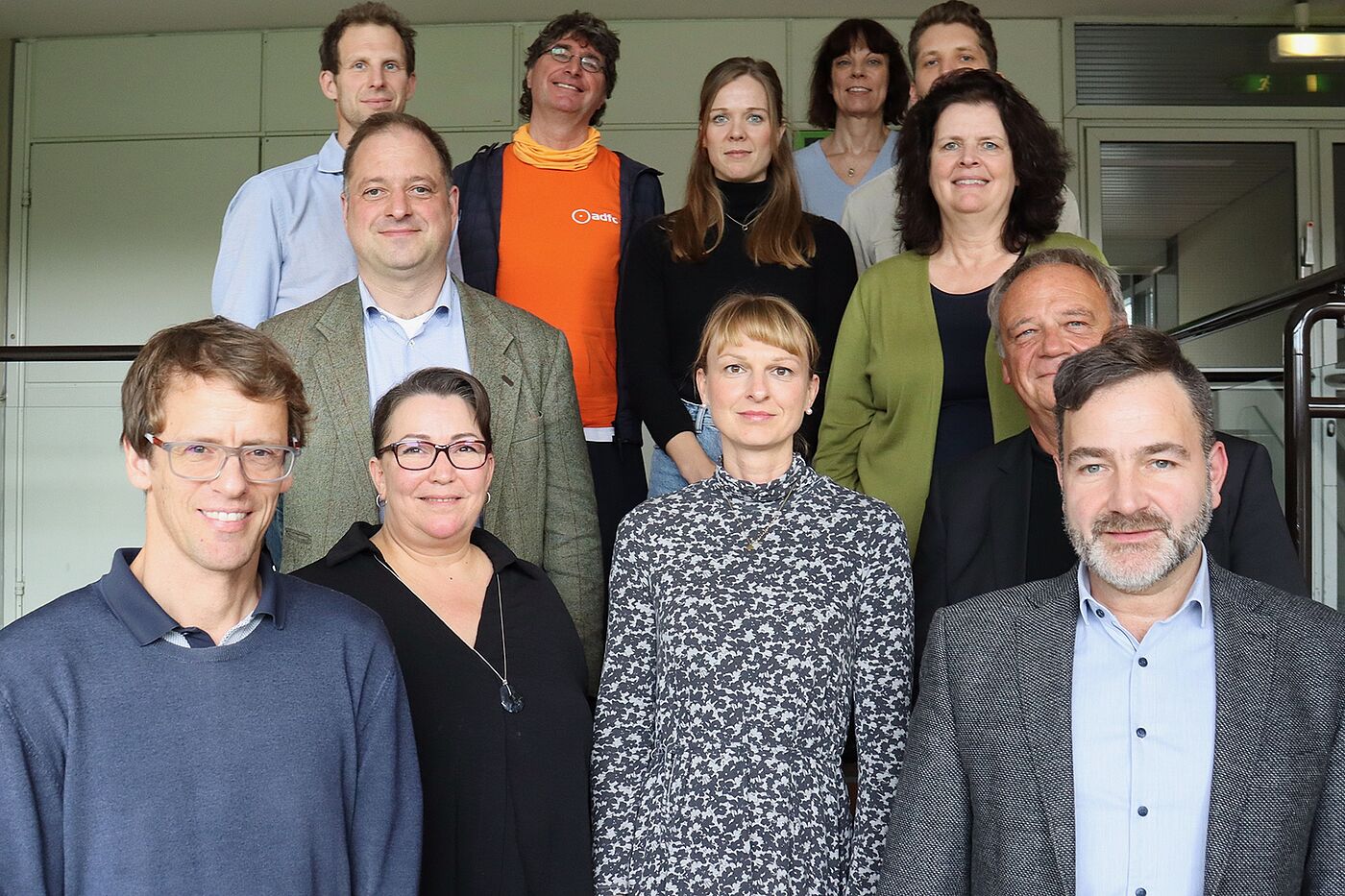2024_11_04_FFA_BASt_c_BASt Zwölf Menschen stehen auf einem Podest. Man sieht nur ihre Oberkörper. Im Hintergrund ist eine Schrankwand zu erkennen.
