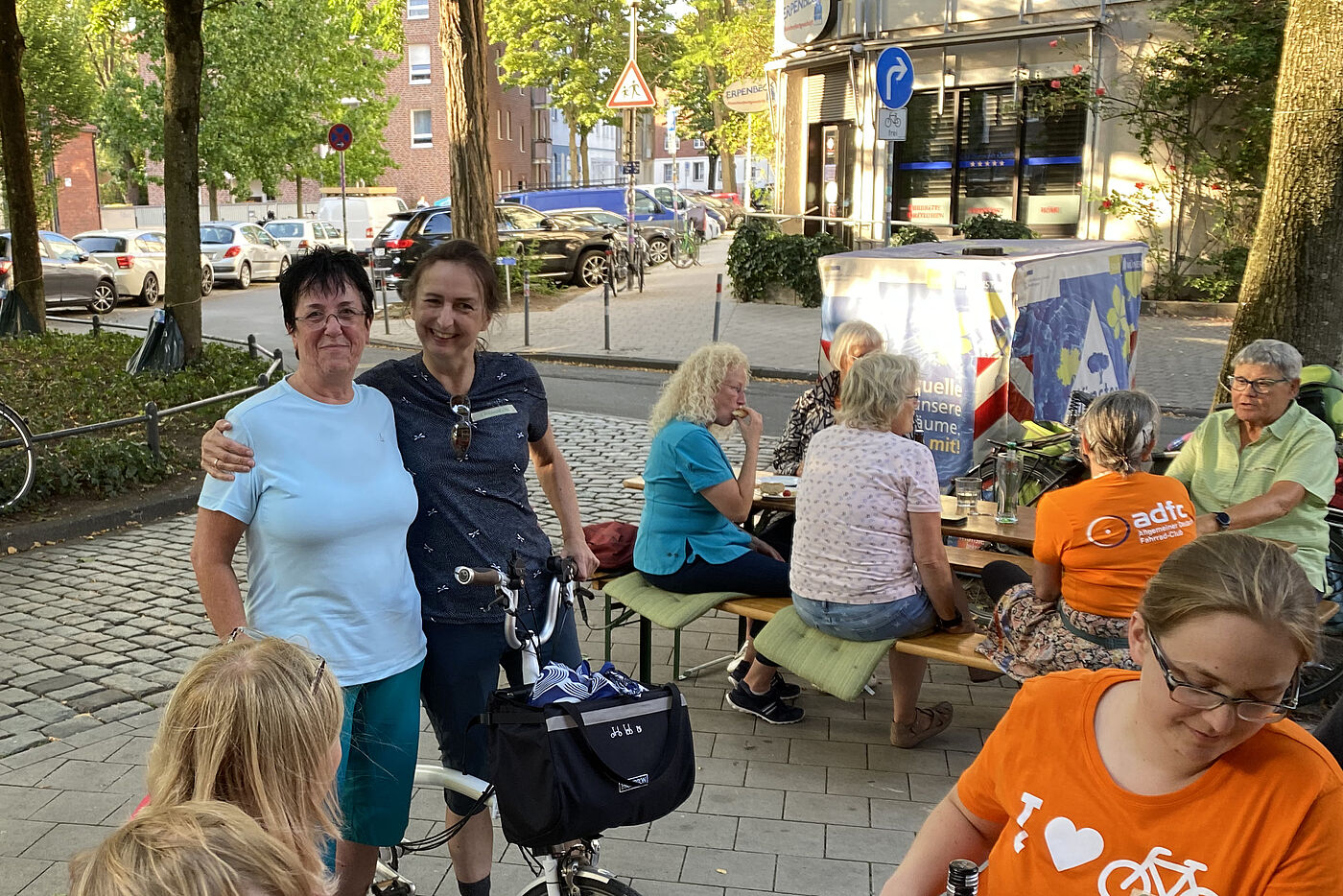 Mehrere Frauen vor der Geschäftsstelle des ADFC Münsterland stehend und auf Bierbänken sitzend genießen das Wiedersehen und den Austausch