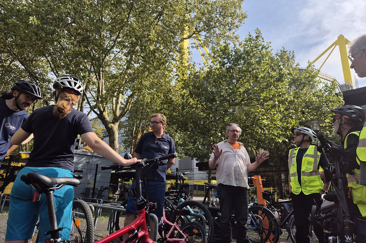 Menschen in Areal der Radwache, im Hintergrund das Stadion. 